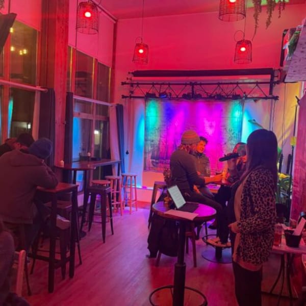 Customers enjoying live music at El Capitan's, illuminated by vibrant red, blue, and purple lights.